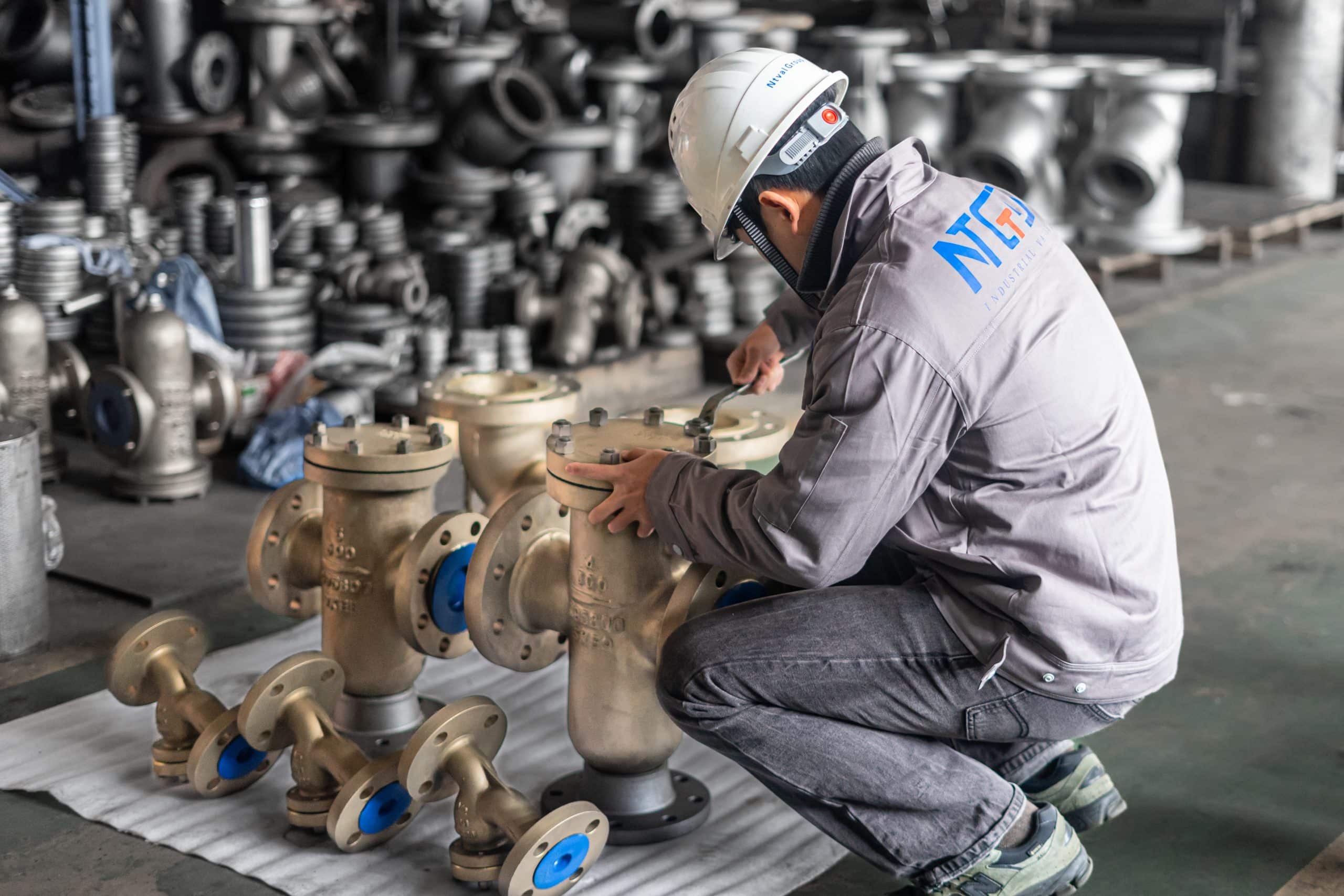 Industrial valve assembly and inspection workshop showing technician performing quality control
