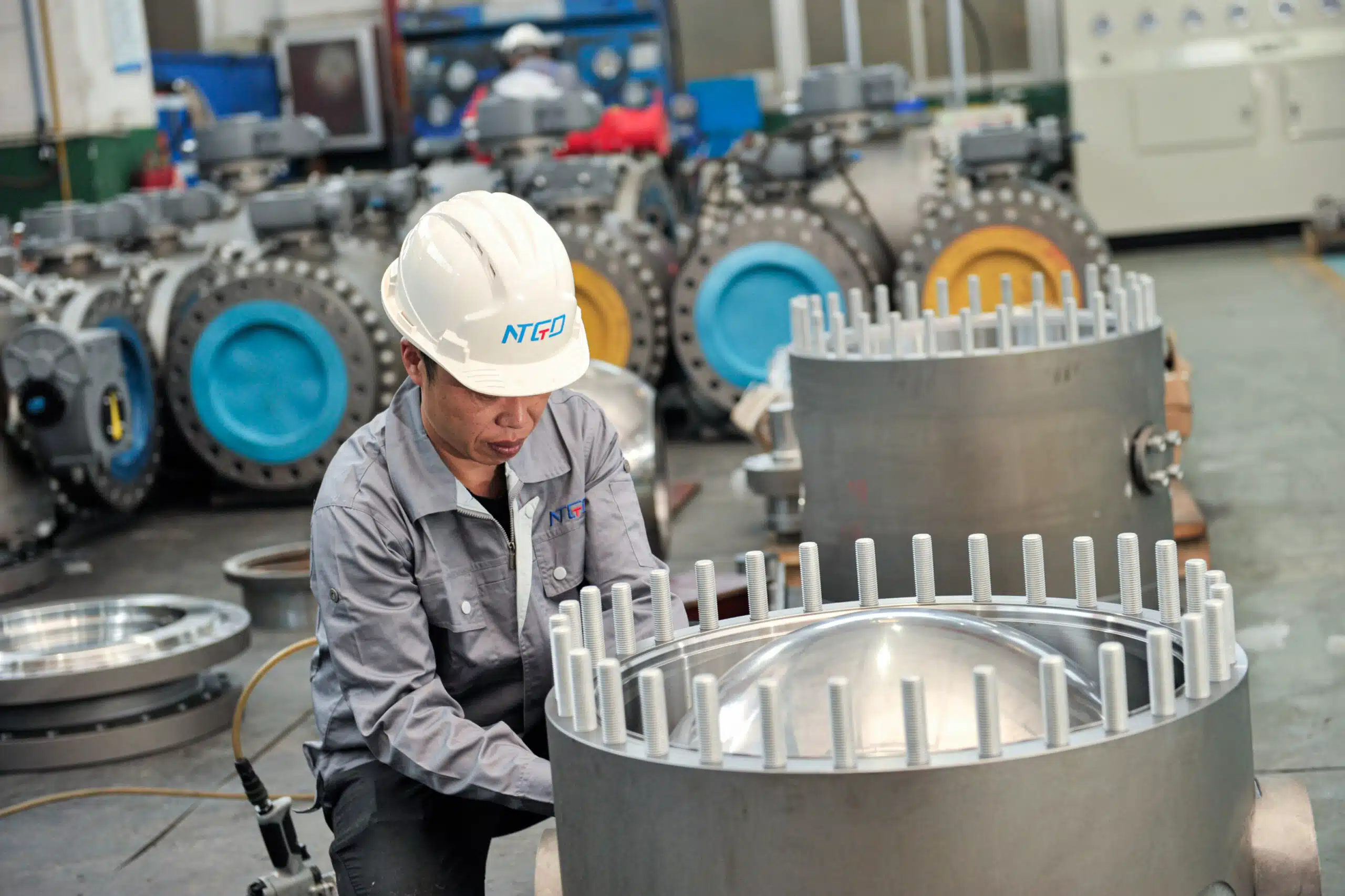 Un técnico de NTGD montando una válvula de bola industrial de gran tamaño en el taller