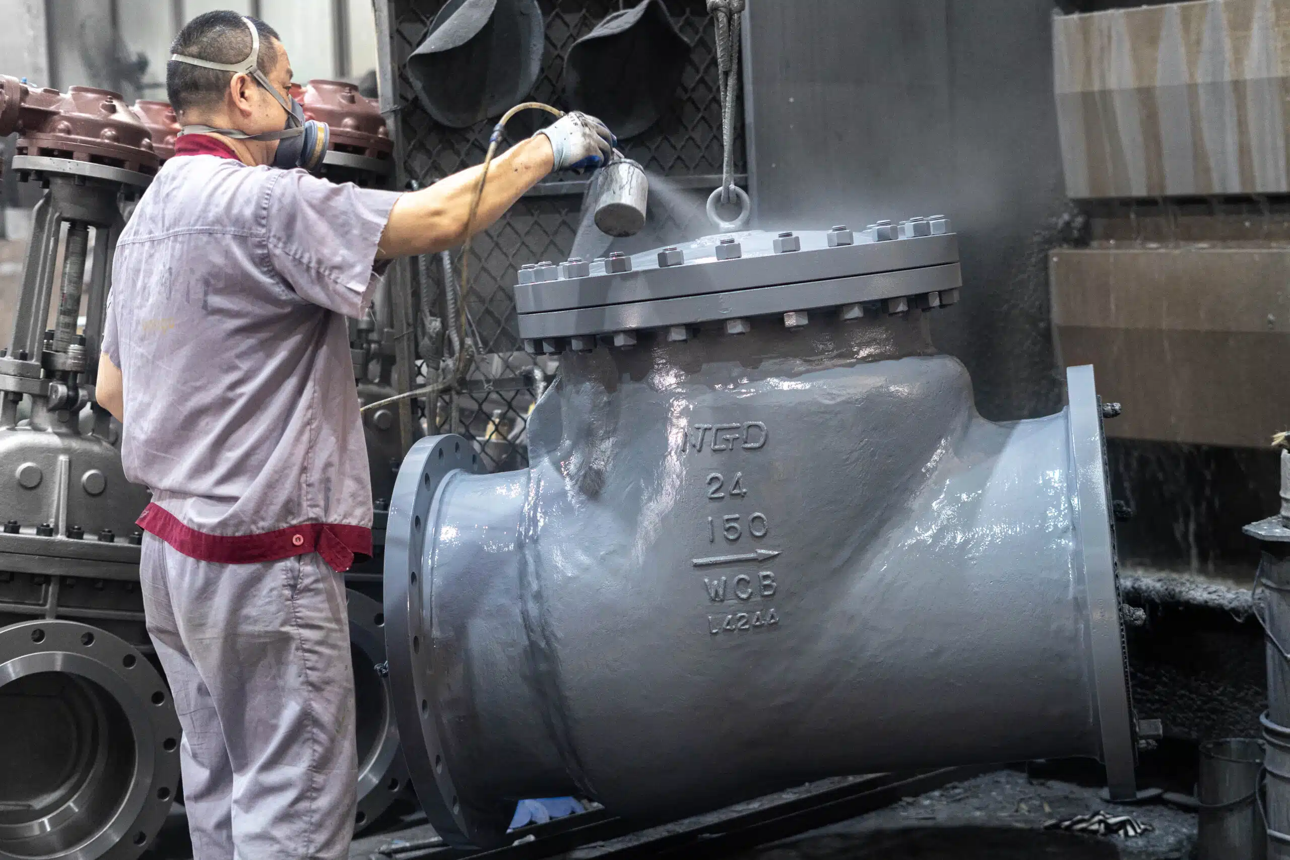 NTGD worker coating a 24-inch Class 150 WCB swing-type check valve in the factory