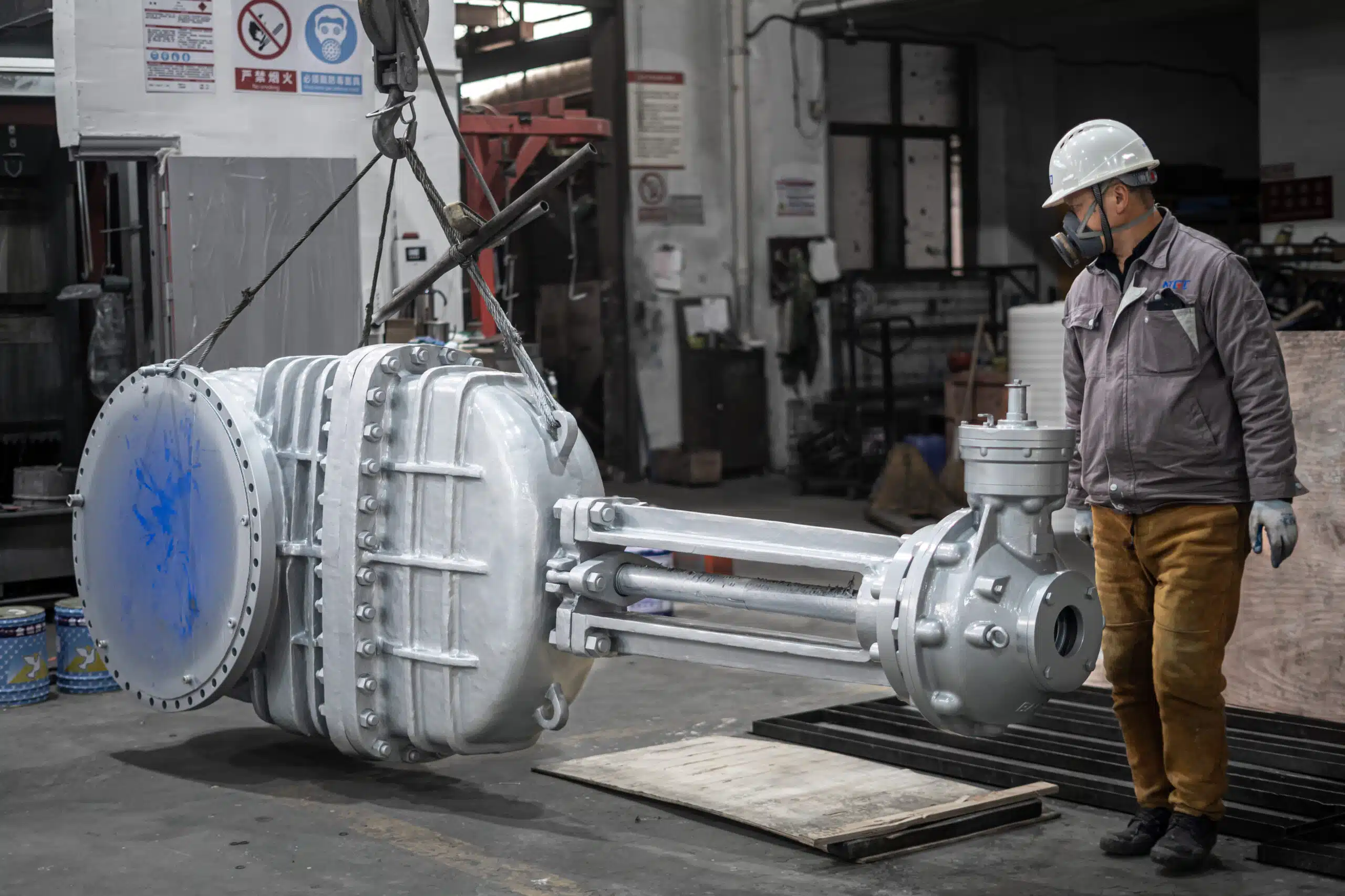 Worker painting a DN700 PN25 industrial gate valve in the workshop