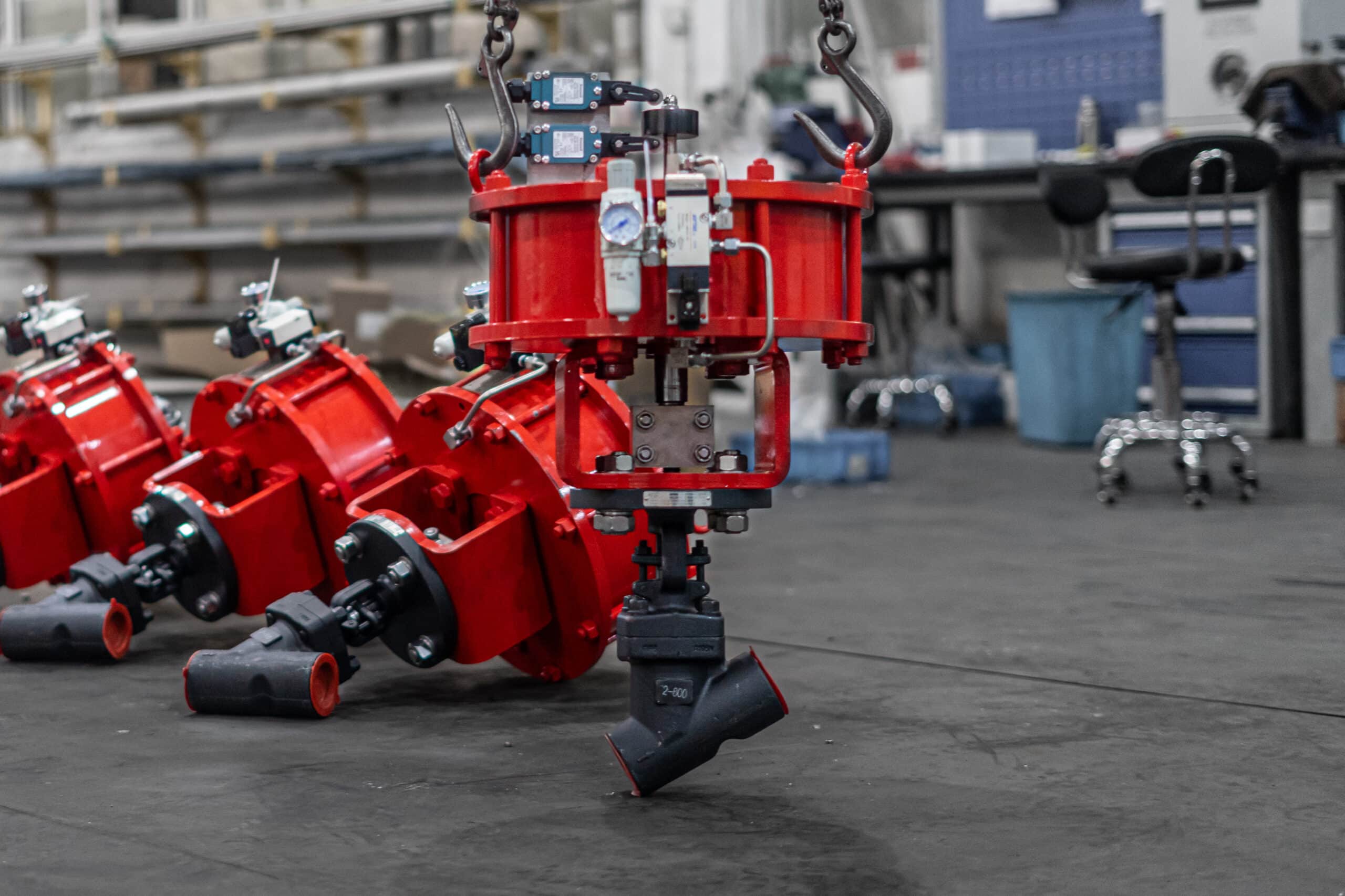 Pneumatically actuated Y pattern globe valve in a workshop with actuator, accessories, and angled valve body.
