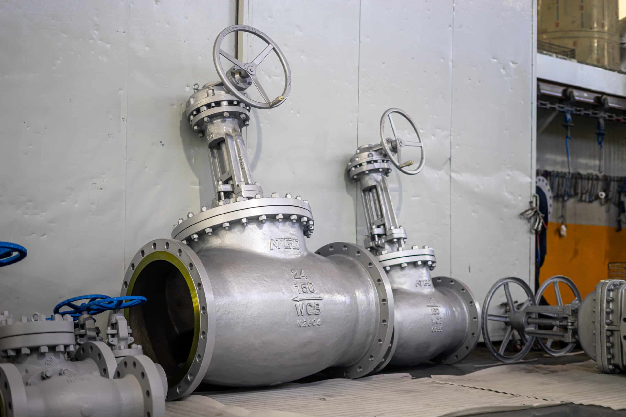 Large flanged globe valves in a workshop with visible size, pressure class, and WCB body markings.