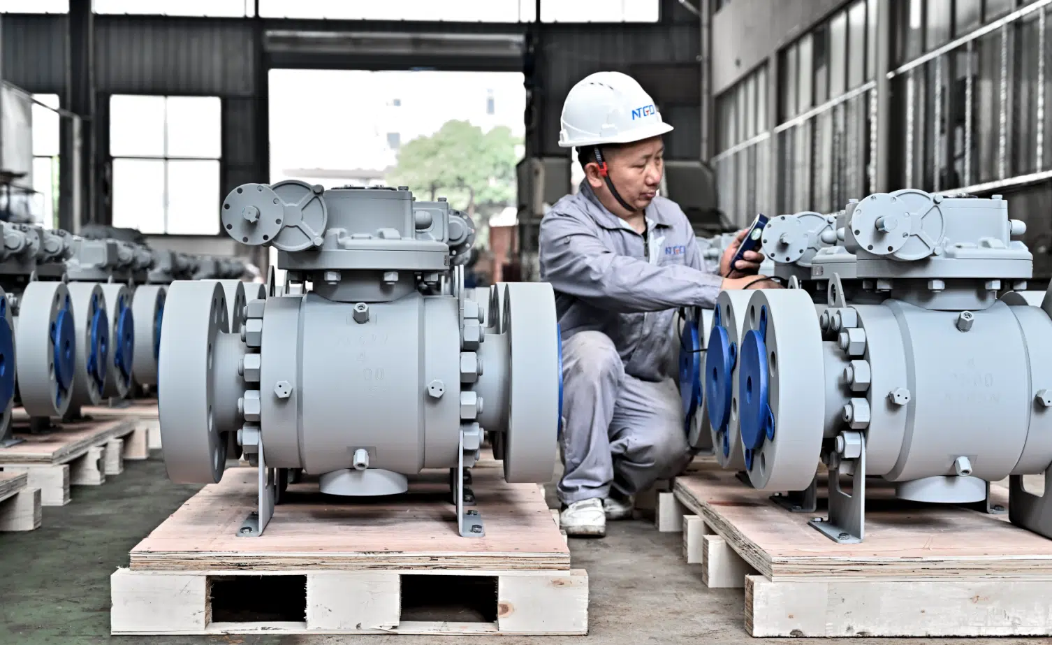 Técnico de NTGD inspeccionando válvulas de bola industriales de gran tamaño en el taller