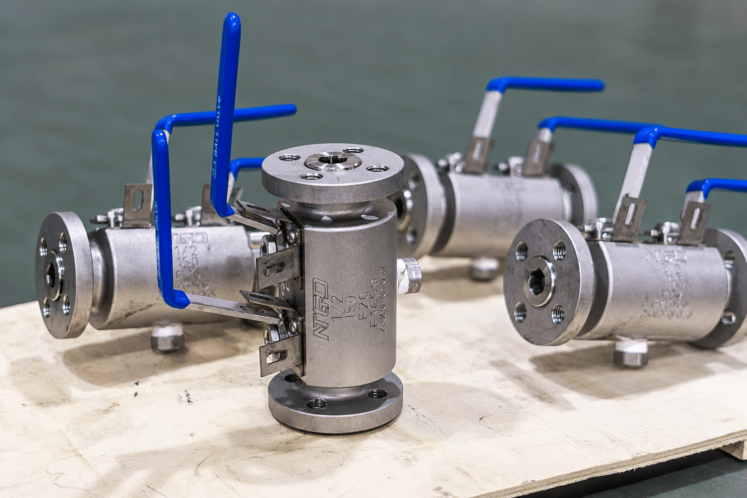 Industrial DBB ball valves with blue handles in a workshop manufacturing setting