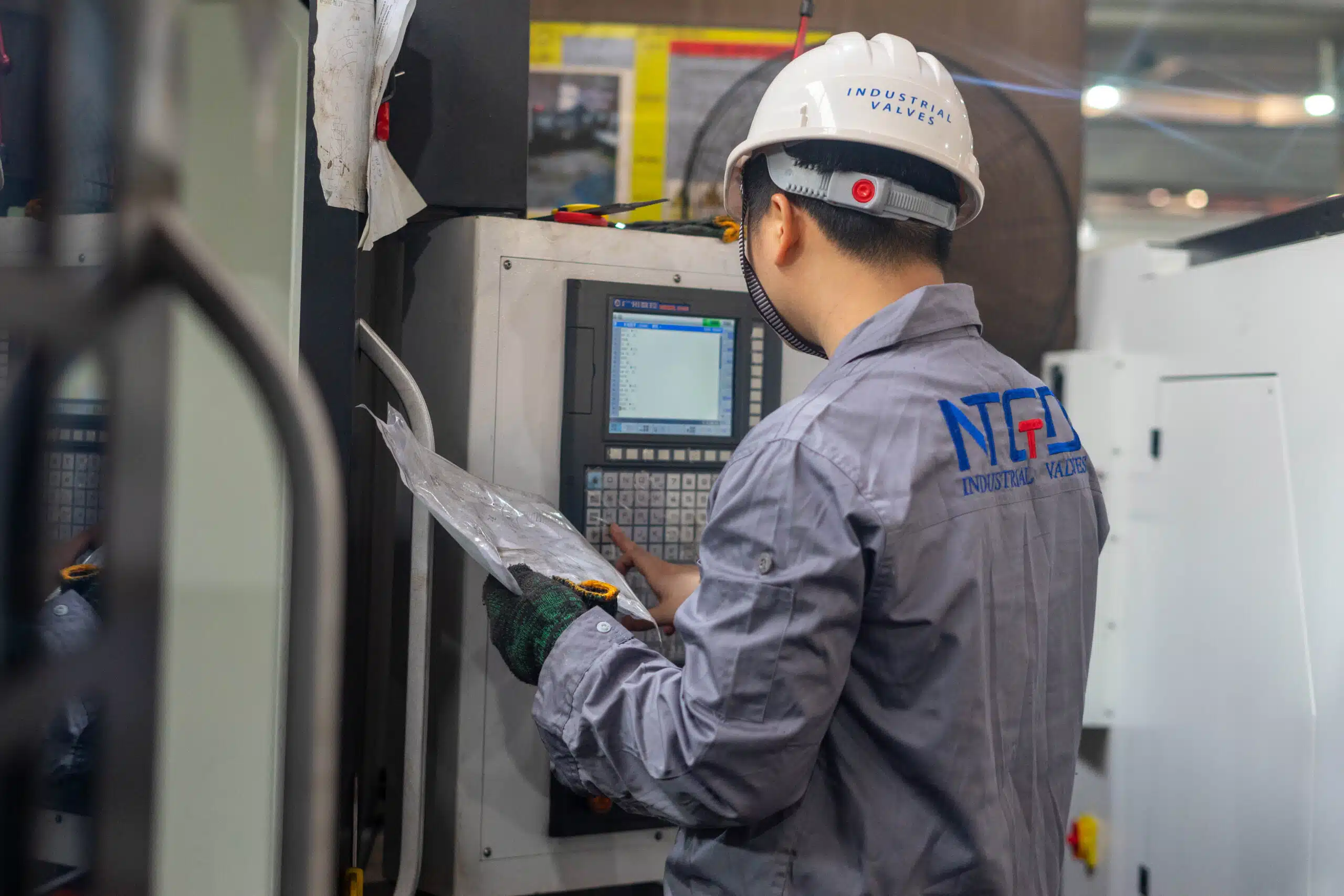 NTGD valve factory worker checking machining control during industrial valve production