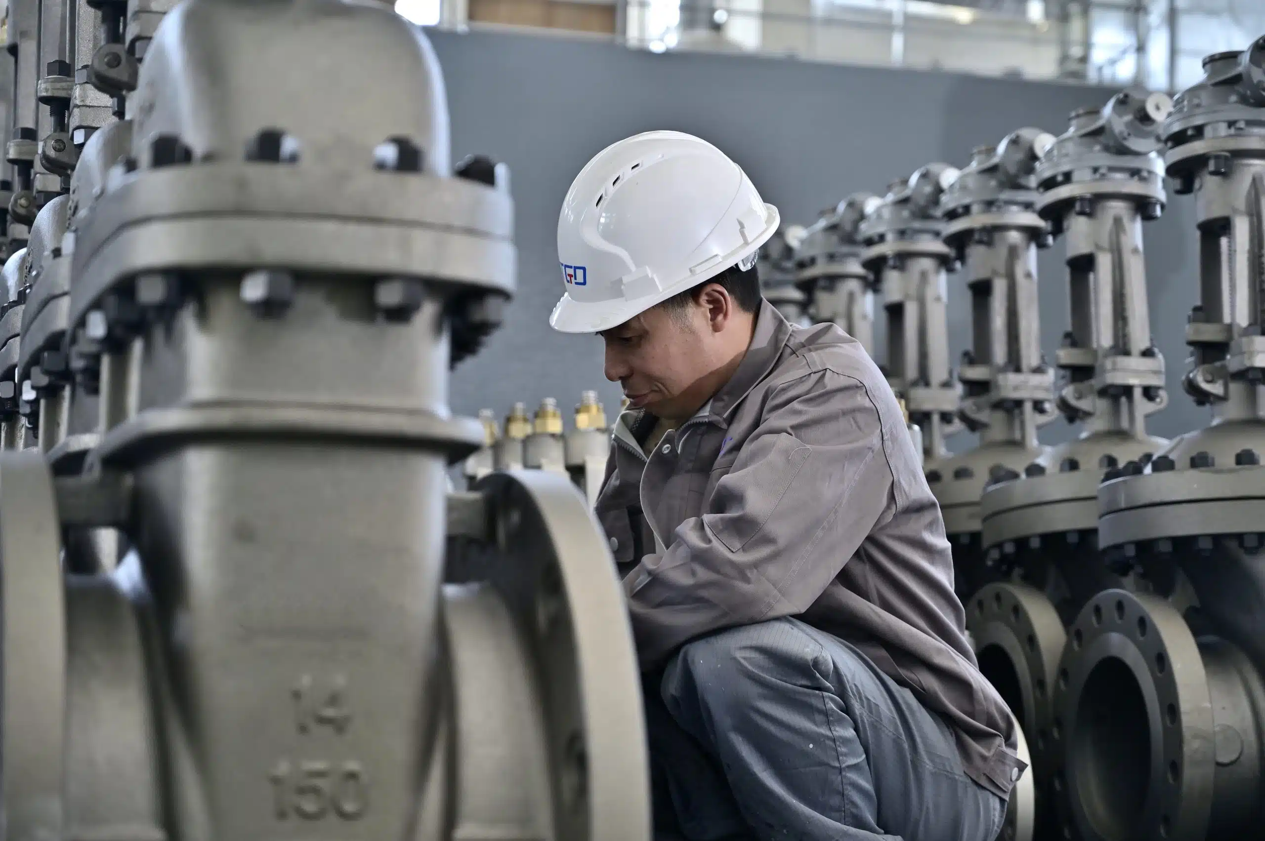 Engenheiro inspecionando válvulas de gaveta industriais em uma configuração de revisão de aplicação de fábrica