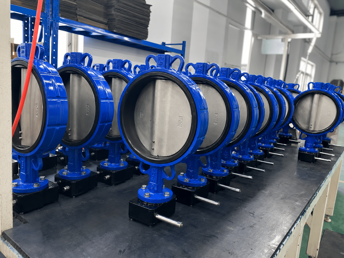 Real workshop photo of blue butterfly valves arranged in a product row.