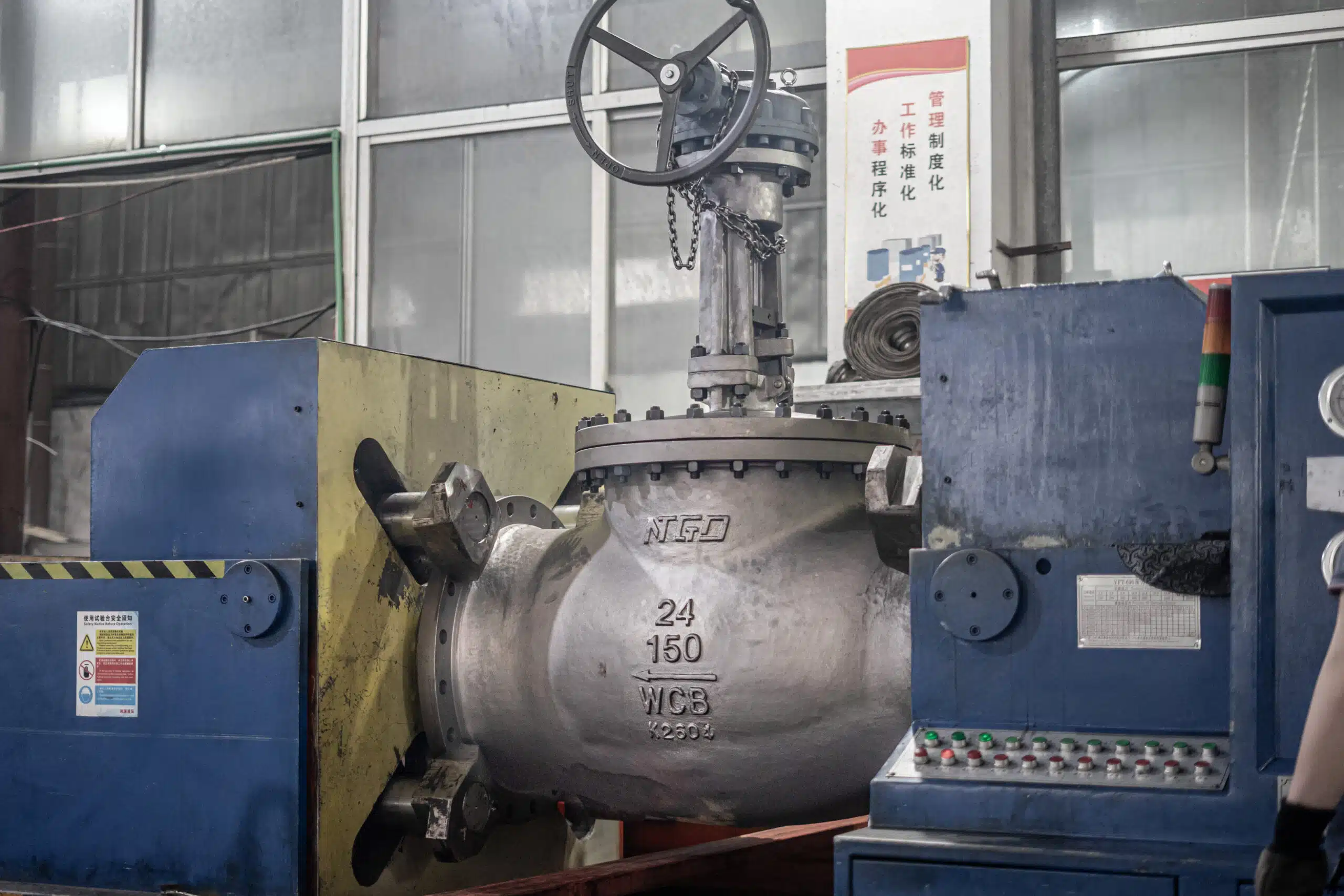 Válvula globo industrial grande em teste de pressão em uma oficina com marcação visível no corpo.