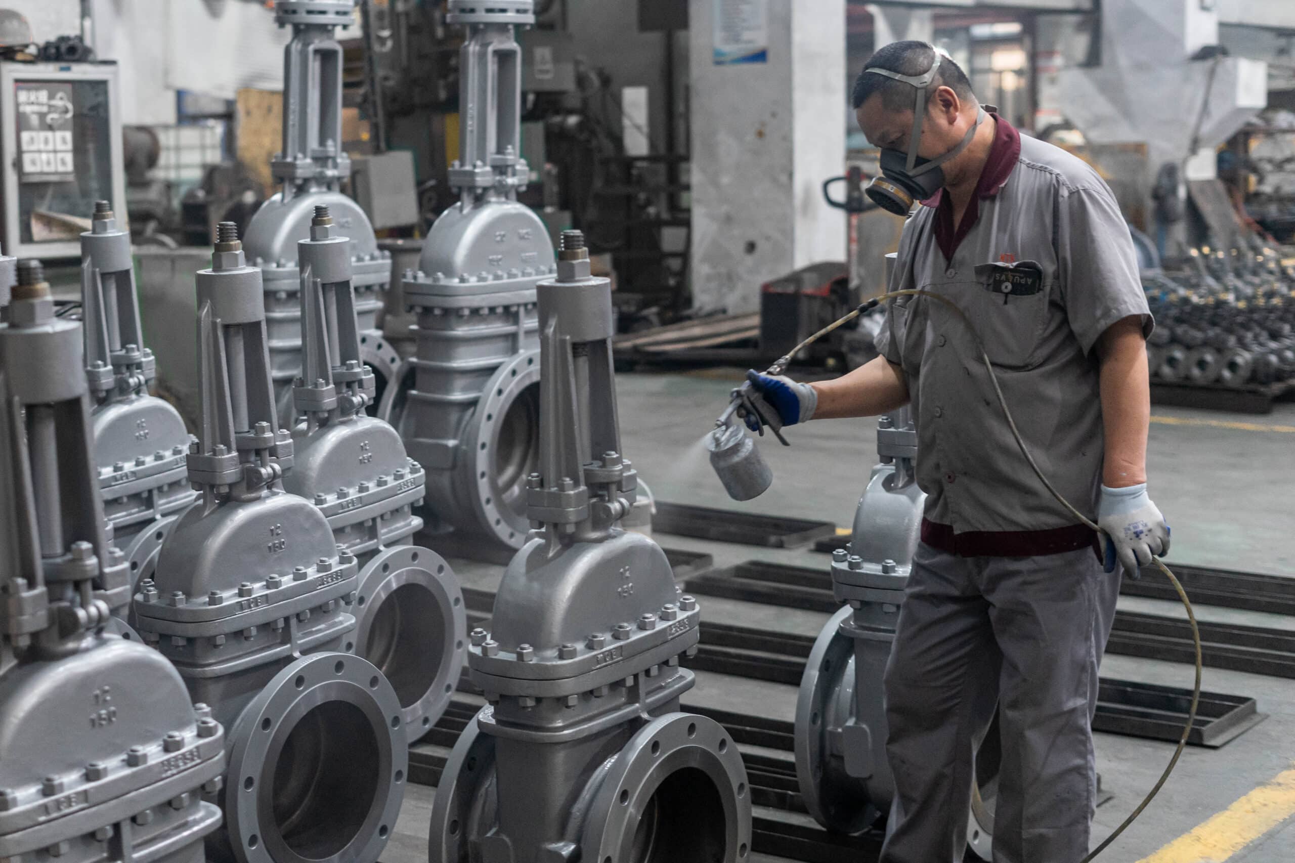 Worker applying protective coating to industrial valves for corrosion protection