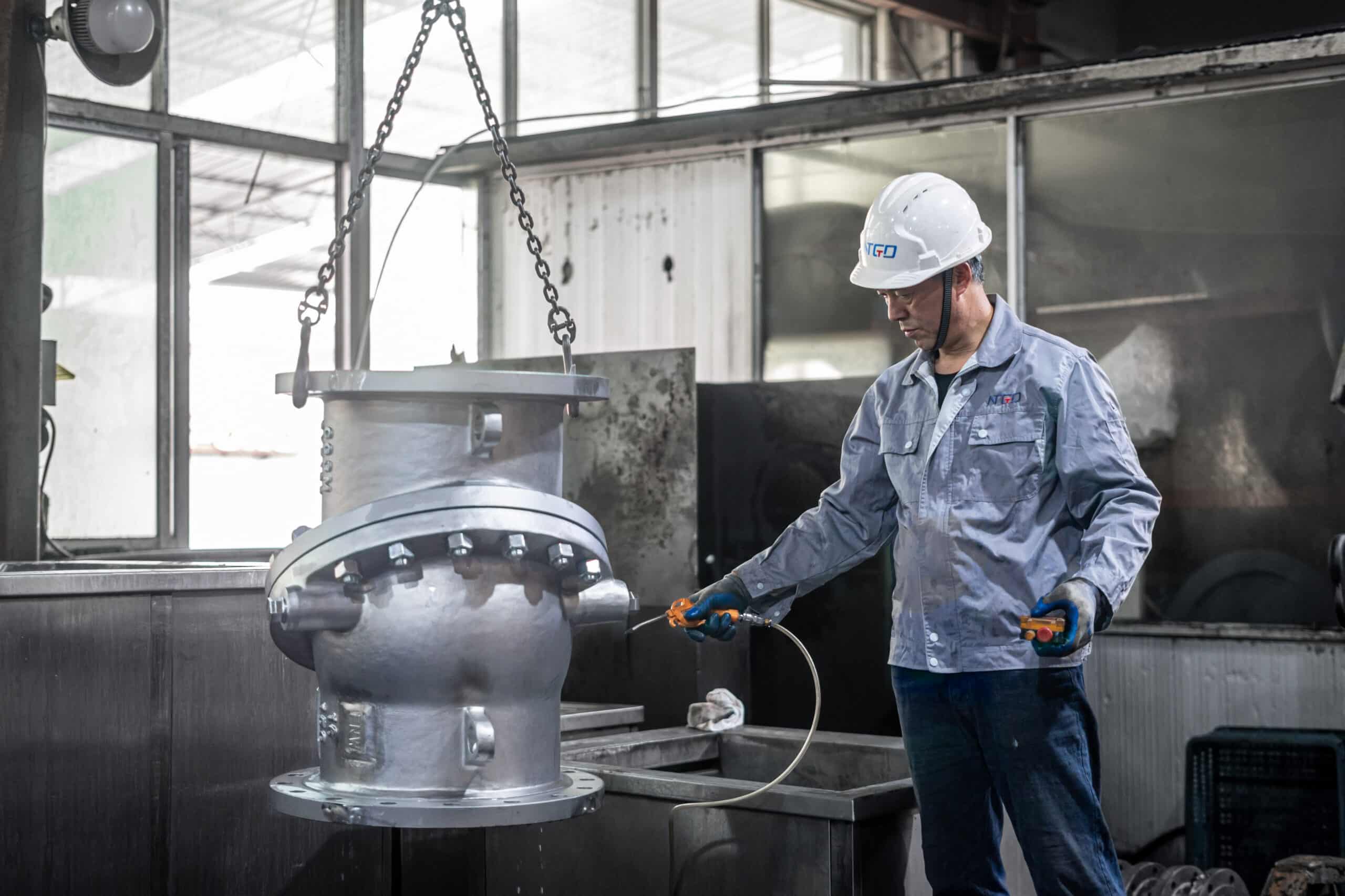 Técnico inspecionando uma válvula industrial em uma oficina de fábrica antes da revisão final da aplicação