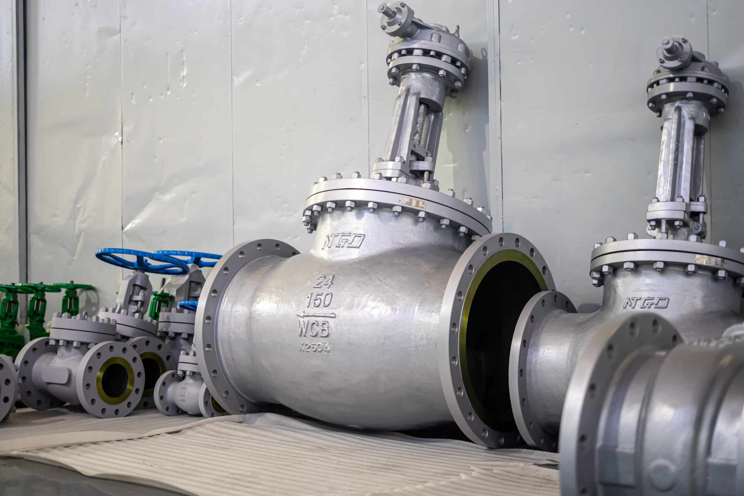 Large flanged globe valves in a factory showing body, bonnet, flanges, and handwheel structure.