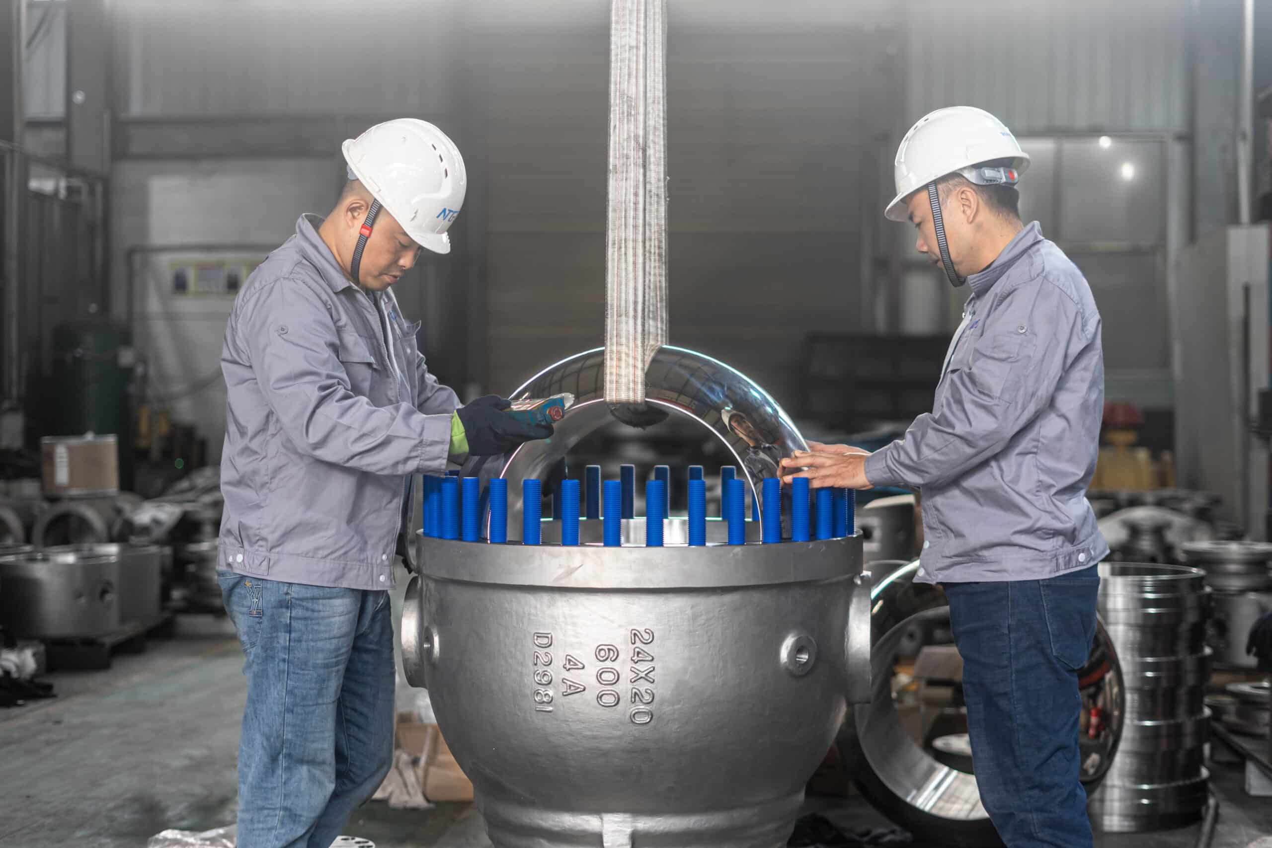 Technicians inspecting a large split-body ball valve during workshop assembly